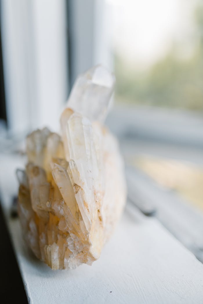Close-up of a clear quartz crystal cluster on a white windowsill, radiating energy.