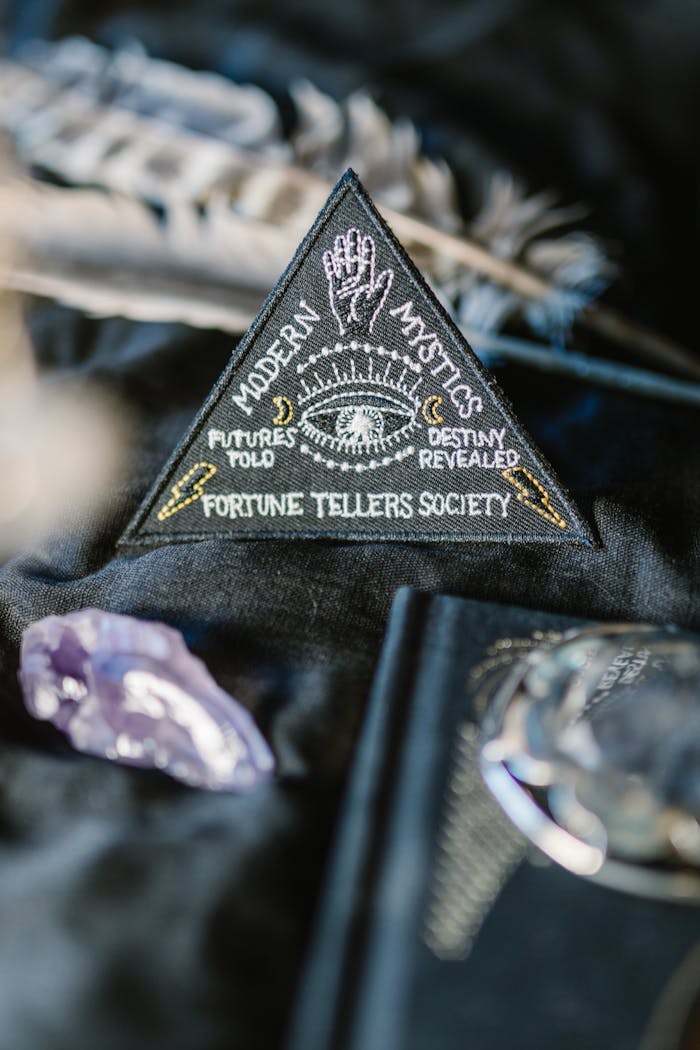 my-path A mystical triangle patch with fortune-telling themes surrounded by crystals and feathers on dark background.