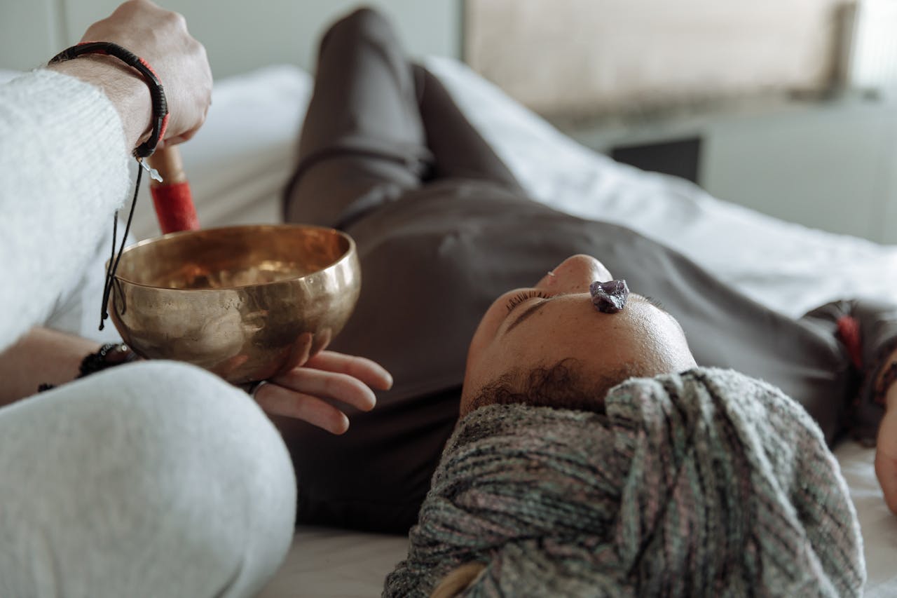 about-me A serene relaxation therapy session with a Tibetan singing bowl and crystal on forehead, promoting spiritual healing.